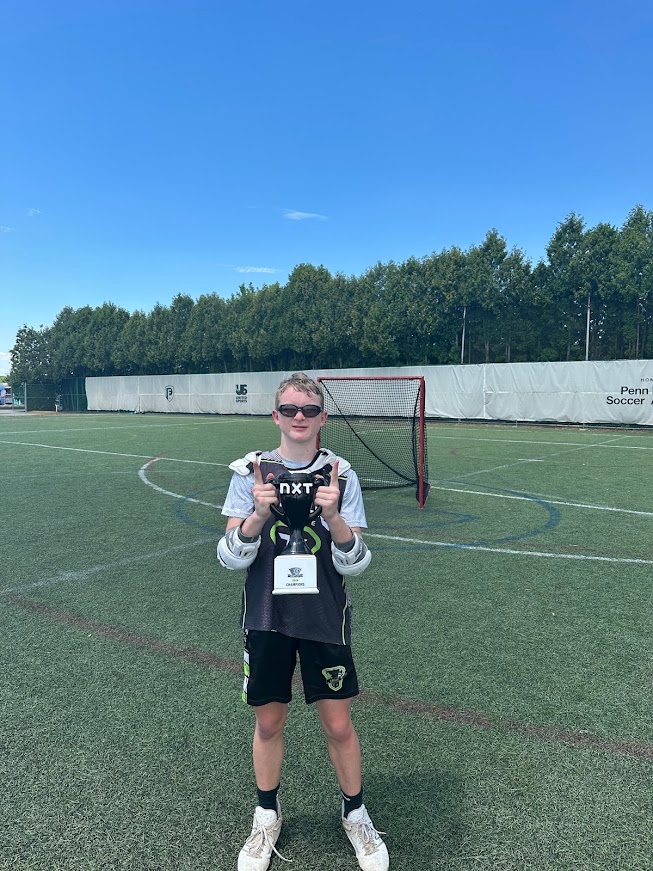 Holding an NXT championship trophy on the field